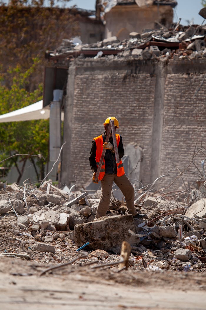 A construction worker in a reflective vest stands among building rubble in Malatya, Turkey.